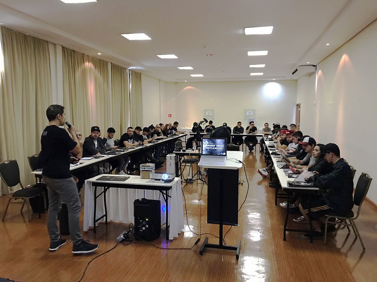 Fernando Souza dando aula em um workshop de tatuagem preto e branco em 2015, para uma sala cheia